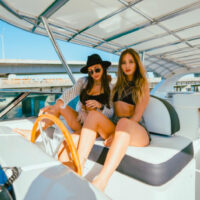 Two guests posing for a picture on the helm of this Miami boat charter.