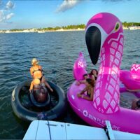 Girls playing on water toys behind this Miami boat charter.